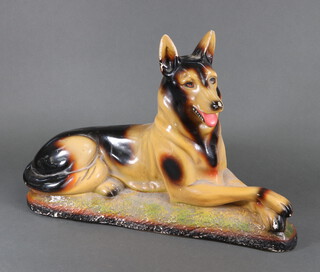 A plaster figure of a reclining German Shepherd dog 