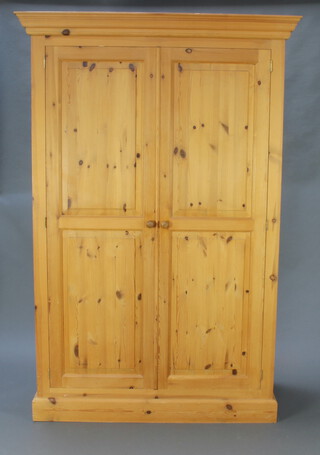 A Victorian style pine wardrobe with moulded cornice enclosed by panelled doors 194cm h x 129cm w x 60cm d 