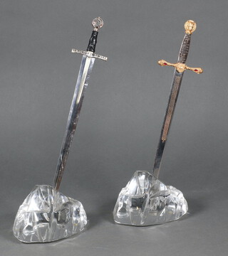 Two Excalibur style paperweights in the form of a glass rock with sword 32cm x 12cm x 9cm 