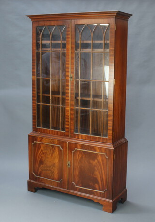 A Georgian style mahogany bookcase on cabinet with moulded cornice, fitted shelves enclosed by astragal glazed panelled doors, the base enclosed by panelled doors, raised on bracket feet 186cm h x 101cm w x 33cm d 