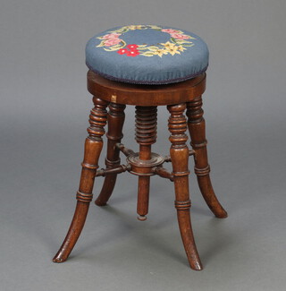 A William IV circular revolving adjustable piano stool with Berlin woolwork seat, raised on outswept turned supports 54cm x 30cm 