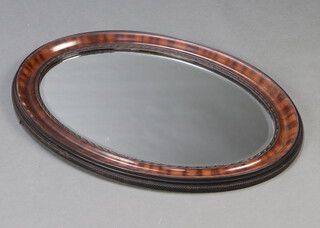 A 1920's oval bevelled plate wall mirror contained in a tortoiseshell effect frame 60cm x 84cm 