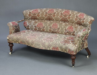 A Victorian 2 seat sofa of serpentine outline upholstered in floral patterned material, raised on turned supports ending in casters 72cm h x 148cm w x 51cm d  