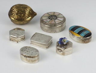 Six white metal pill boxes together with a brass acorn nutmeg holder 
