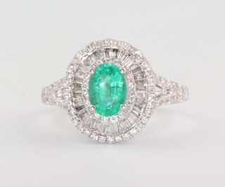 A white metal 14k oval emerald and diamond cluster ring, the centre stone 0.8ct the brilliant and baguette cut diamonds 0.75ct, 3.4 grams, size N 1/2 