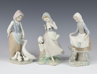 A Lladro figure of a girl with a dove 22cm, ditto with a rabbit 21cm and another with a goose 23cm 