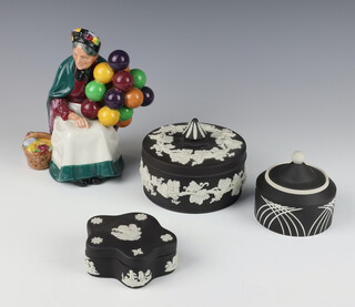 An unusual Wedgwood black basalt pot and cover with geometric decoration 8cm, ditto circular box and cover and a scallop box and cover together with a Royal Doulton figure The Balloon Seller HN1315 and a ditto The Boatman HN2417 18cm