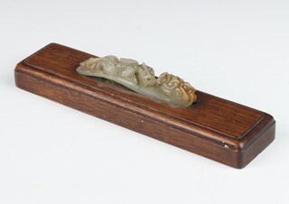 A Chinese carved hardstone belt hook in the form of a dragon mounted on a wooden plinth 9cm 