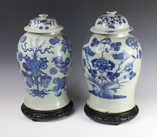 A near pair of antique style Chinese blue and white baluster vases and covers decorated with birds amongst flowers with wooden stands 47cm  
