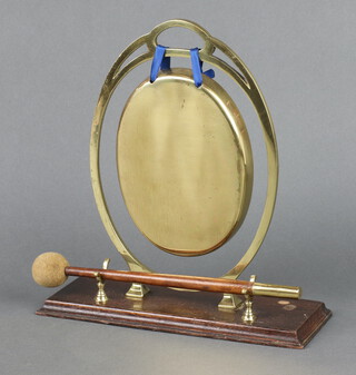 An Art Nouveau oval brass tea gong raised on a rectangular oak base, complete with beater, 28cm x 26cm x 10cm