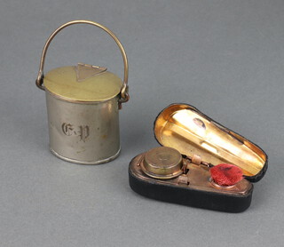 A Victorian brass novelty inkwell in the form of a violin case fitted inkwell and pen wipe 2.5cm x 8cm x 3cm together with an inkwell in the form of an oval milk canister with swing handle and striker to the base 6cm x 5cm x 4cm   