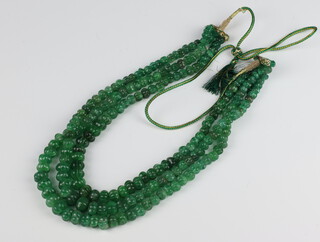 An emerald triple strand carved round bead necklace 60cm 