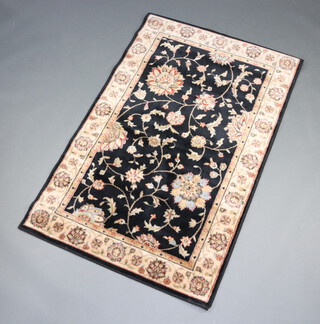 A black and gold ground Persian style machine made rug with floral pattern to the centre within a 2 row border 168cm x 107cm 