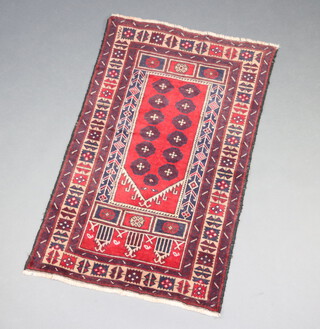 A red and brown ground Baluchi rug with 12 octagons to the centre 132cm x 82cm 