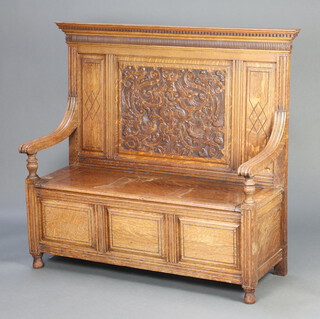 A Victorian carved light oak settle with moulded and dentil cornice, panelled back, the seat with hinged lid and raised on bun feet 122cm h x 134cm w x  49d (seat 105cm x 30cm) 