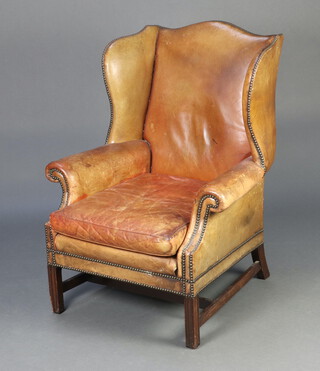 A Georgian style winged armchair upholstered in brown leather, raised on square supports 107cm h x 80cm w x 64cm d (seat 43cm x 50cm) 