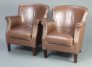 A pair of 1930's style club armchairs upholstered in brown leather material, raised on outswept supports 77cm h x 66cm w x 50cm d (seats 34cm x 39cm)  