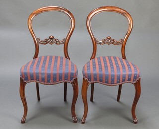 A pair of Victorian walnut balloon back chairs with carved and pierced mid rails, raised on cabriole supports 85cm x 43cm x 41cm 