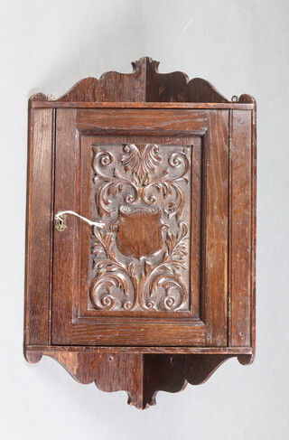 A Victorian oak hanging corner cabinet enclosed by a carved panelled door 65cm h x 27cm w x 27cm d 