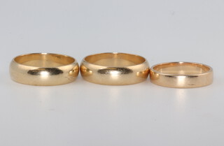 Two 9ct yellow gold wedding bands and a yellow metal ditto, sizes M, P and P, 12.2 grams 
