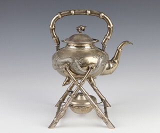 A Chinese repousse silver tea kettle decorated with dragons chasing the flaming pearl with bamboo effect handle and spout, raised on a bamboo effect stand with burner, maker Wing Nam & Company, 27cm to the handle, 930 grams 