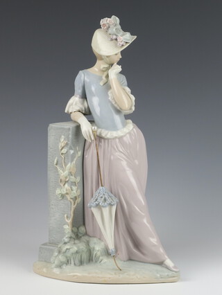 A Lladro figure of a lady standing beside a wall holding a parasol 36cm 