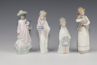 A Lladro figure of a girl holding a lamb 23cm, ditto of a kneeling girl 4673 17cm, a boy 23cm and a girl with kitten 21cm 