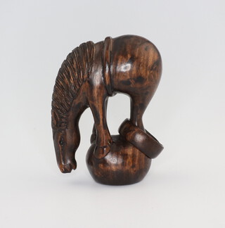 A Japanese carved hardwood Netsuke of a horse with a reticulated ring to its back legs, signed 5cm 