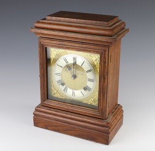 An Ansonia striking mantel clock with 17cm gilt dial, silvered chapter ring and Roman numerals, contained in an oak case 24cm x 24cm x 12cm, complete with pendulum and key 