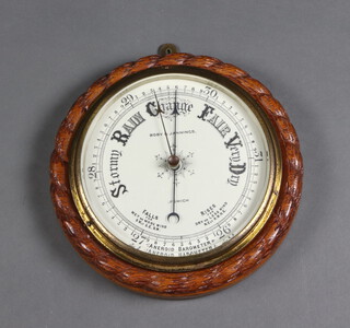 An aneroid barometer with 18cm porcelain dial marked Bobby and Jennings Ipswich, contained in a carved oak case 8cm x 28cm 