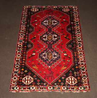 A red and blue ground Persian rug with 3 stylised medallions to the centre with bird and animal decoration 257cm x 169cm 
