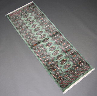 A green ground Bokhara runner with 14 octagons to the centre within a multi row border 189cm x 68cm 