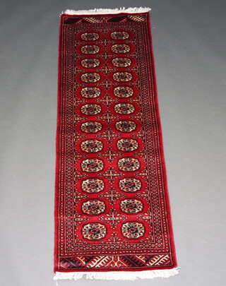 A red ground Bokhara runner with 24 octagons to the centre 180cm x 64cm 