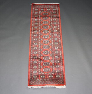 A rust ground Bokhara runner with 12 octagons to the centre 184cm x 64cm 