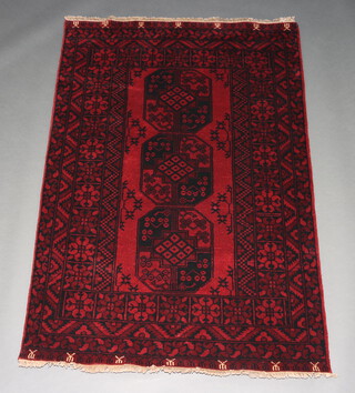A red and black ground Afghan rug with 3 octagons to the centre within a 4 row border 183cm x 122cm 