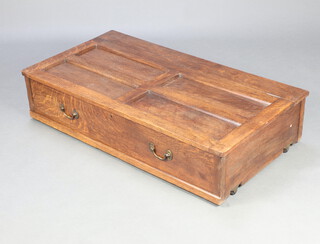 A 1930's rectangular panelled oak underbed storage unit raised on casters 26cm h x 118cm w x 63cm d 