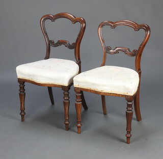 A pair of Victorian carved rosewood spoon back chairs with shaped mid rails and overstuffed seats, raised on turned supports 83cm h x 47cm w x 40cm d (seats 28cm  25cm) 