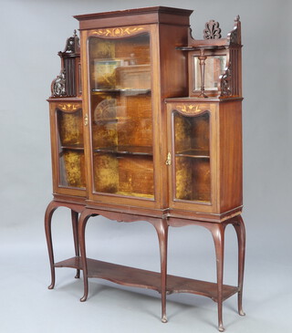 An Edwardian Art Nouveau inlaid mahogany display cabinet, the centre section fitted shelves enclosed by panelled doors, flanked by a pair of niches above cupboards enclosed by panelled doors, having an undertier and raised on cabriole supports 174cm h x 123cm w x 28cm d 