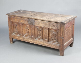 A 17th/18th Century bleached carved oak coffer with hinged lid, the sides and front inscribed 'Give To The Por For The Lords Sake'. The front four panel with carved reliefs of a man, a flower , a leaf and a woman - 63cm h x 130cm w x 47cm d 