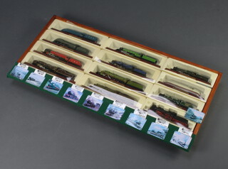 Twelve various Atlas editions of model locomotives contained in a pine wall mounting display case 45cm h x 96cm w x 7cm d 
