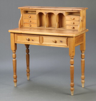 A Victorian style pine writing table, the raised superstructure to the back fitted  pigeon holes and 6 short drawers, the base fitted 2 drawers, raised on turned supports 107cm h x 96cm w x 45cm d (contact marks, light scratches in places) 

