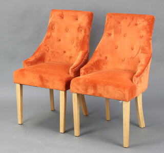 A pair of beech framed dining chairs, the seats and backs upholstered in buttoned orange material, raised on square supports 93cm h x 51cm w x 46cm d 
