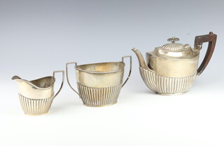 A Victorian and later matched silver tea service with demi-reeded decoration comprising twin handled sugar bowl and cream jug, Sheffield 1851, teapot London 1898, gross weight 918 grams including wooden handle and finial  
