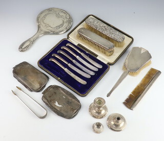 A set of 5 tea knives with silver pistol grip handles, a pair of Georgian silver sugar tongs, silver backed hand mirror, pair of clothes brushes, silver backed hair brush, comb, 2 silver brush backs and a pair of silver candlesticks (f)  