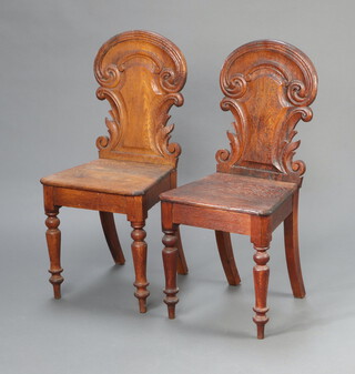 A pair of Victorian carved oak hall chairs with solid seats and backs raised on turned supports 90cm h x 40cm x 36cm 