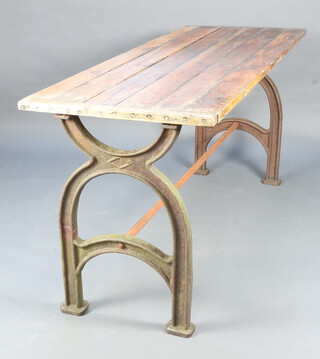 A 20th Century industrial iron and pine rectangular table, the top formed of 6 planks, raised on 2 arched iron supports and with iron stretcher 99cm h x 231cm l x 79cm d 