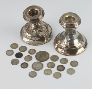 Two silver stub shaped candlesticks 7cm (f) and a collection of minor silver coinage 