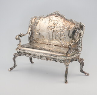 A Continental repousse silver miniature model of a sofa, raised on cabriole legs decorated with figures 7cm, 50 grams 