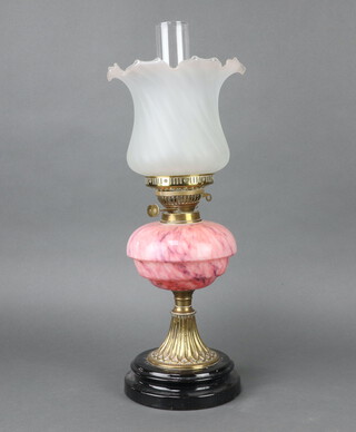 A Victorian pink opaque glass oil lamp reservoir, raised on an embossed gilt metal and ceramic base with pink opaque shade and chimney 59cm h x 16cm 
