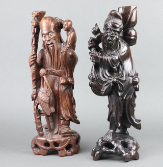 An Eastern carved hardwood figure of a standing deity with bird 40cm h x 13cm and 1 other 42cm x 13cm 